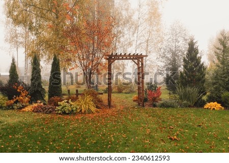 autumn garden view in october with wooden archway. Rustic natural fall garden