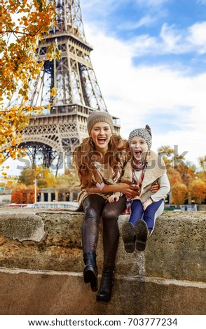 Autumn getaways in Paris with family. Portrait of smiling mother and child tourists on embankment in Paris, France having fun time