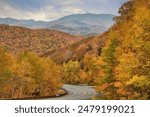 Autumn glory in New England. Stunning view of forest, mountains, and vibrant fall foliage from top of Kinsman Notch in the White Mountains of New Hampshire.