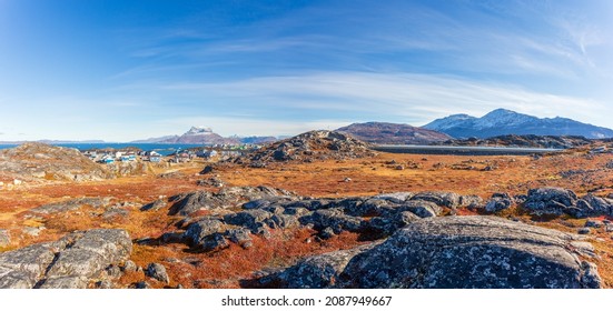 Autumn greenlandic  tundra with orange grass, stones, Inuit settlement and Sermitsiaq mountain in the background, Nuuk, Greenland