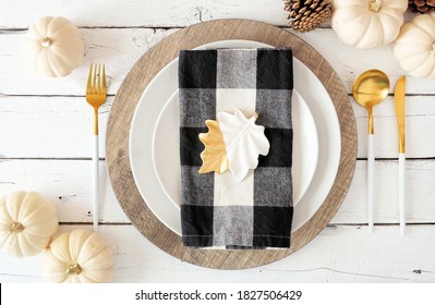 Autumn Harvest Or Thanksgiving Dinner Table Setting With Plates, Flatware, Buffalo Plaid Napkin, Pumpkins And Decor. Top View On A White Wood Background.