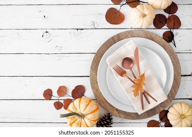 Autumn Harvest Or Thanksgiving Dinner Table Setting With Plates, Flatware, Napkin And Fall Decor. Overhead View Corner Border On A White Wood Background With Copy Space.