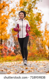 Autumn Healthy Middle Aged Mature Woman In Her Fifties Exercising Cardio Training For Active Lifestyle. Jogging Asian Lady Running Outdoor In Park.