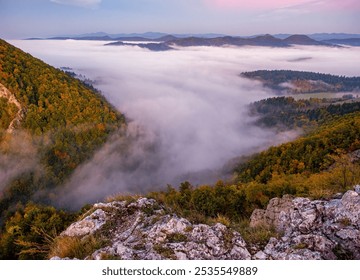 Autumn hiking, Rocky, forested hill emerges from the valley in the mist. Beautiful morning in the mountain landscape with mists. Morning fog. Sulovske skaly, Velky Manin Povazie - Powered by Shutterstock