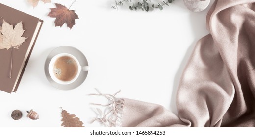 Autumn home cozy composition. Dried autumn leaves, cup of coffee, book, scarf, flowers on white background. Fall background. Flat lay, top view, copy space
