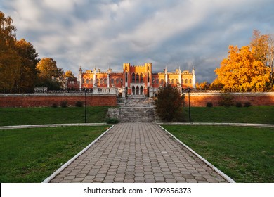 Autumn horizontal landscape: ancient staircase leads through landscape park with yellowed trees to the main Gothic revival style house of old aristocratic estate against a dramatic sunset sky - Powered by Shutterstock