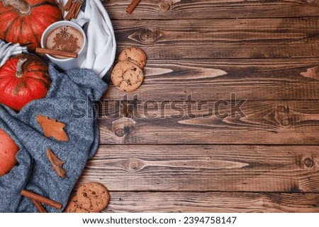 Autumn hot spicy coffee and sweet cookies on wooden rustic table. Dry fall leaves, spices, grey warm woolen scarf top view. Festive cozy thanksgiving template with copy spacy 