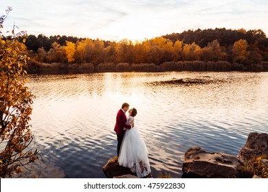 Autumn lake surrounds  wedding couple standing on the stone