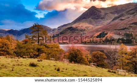 Autumn landscape of Buttermere lake in Cumbria, Lake District. Dramatic sunset in fall season colors and lake reflections in the North of England, UK. Popular destination in the mountains. 