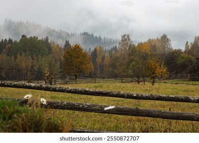 Autumn landscape in Carpathian mountains. Tranquil rural landscape with autumn forest and wooden fence. Empty pasture with foggy mountains and forest. Scenic misty nature in November.  - Powered by Shutterstock