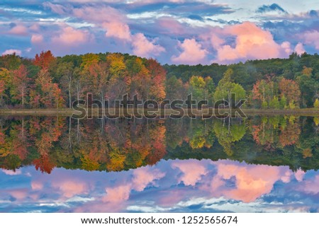 Autumn landscape at dawn of the shoreline of Deep Lake with mirrored reflections in calm water, Yankee Springs State Park, Michigan, USA