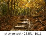 Autumn landscape featuring stone steps going uphill on a hiking trail passing through a colorful forest at Devil’s Lake State Park near Baraboo, Wisconsin.