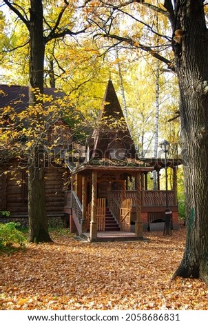 Autumn landscape. An old wooden hut among fallen leaves and autumn trees. Wooden building. Architecture. Yellow trees near the hut.
