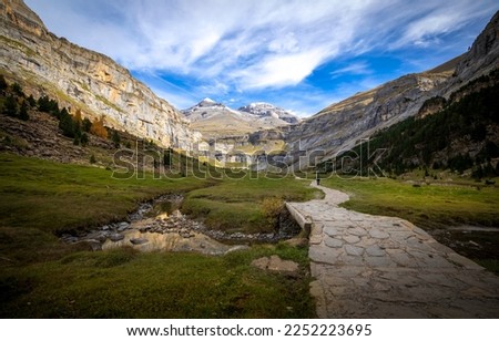 Autumn landscape in the Ordesa y Monte Perdido national park in the Pyrenees, in Huesca, Spain, where you can see a path for hikers with a bridge that crosses a stream