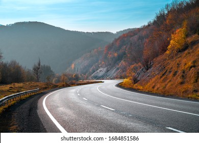 Autumn landscape with road in mountains. Travel background. Highway in mountains under clear blue sky.