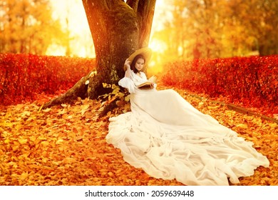 Autumn Landscape. Romantic Victorian Style Woman Reading Book In Park With Orange Maple Leaves. Colorful Fall Season Bright Background