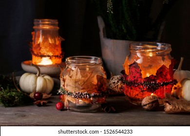 Autumn lantern jars decorated with colorful leaves and heather wreath. Candle inside. 