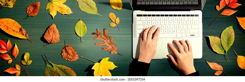 Autumn leaves with person using a laptop computer from above - Powered by Shutterstock