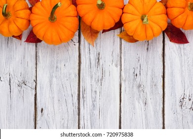 Autumn Leaves And Pumpkin Top Border Over A Rustic White Wood Background