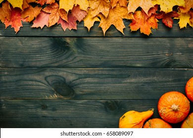 Autumn leaves and pumpkins over old wooden background with copy space - Powered by Shutterstock