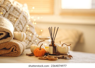 Autumn mood, cozy fall home atmosphere. Aroma diffuser, pumpkins, knitted warm sweaters, burning candles, dry leaves on wooden table. Concept of house decor, apartment seasonal fragrance. Thanksgiving - Shutterstock ID 2364074977