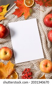 Autumn mood flat lay with notebook, fallen leaves, red berries, apples and warm knitted blanket. Autumn holidays, thanksgiving day, home weekend. Flat lay, top view, copy space