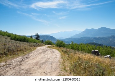 Autumn Morning On A Bad Rural Back Country Dirt Road In The Mountains On The Way To Camping With Wildfire Smoke Haze In The Distance