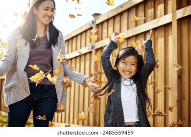 Autumn, mother and asian girl throwing leaves in garden of home together for bonding or love. Family, fall or season with single parent woman and happy child having fun in backyard for wellness - Powered by Shutterstock