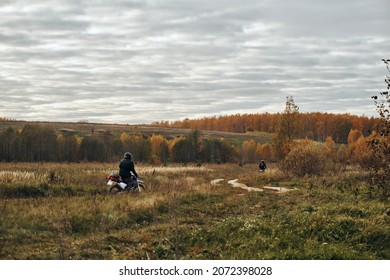 Autumn, Motorcycle Rides On Rough Terrain, Motorcycles. Autumn Landscape, On The Horizon Fields And Forests Are Adjacent To The Sky With Clouds, On A Dirt Road Rides A Motorcyclist.