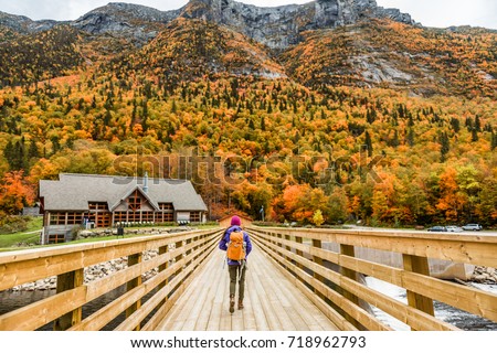Autumn nature hiker girl walking in national park in Quebec with backpack. Woman tourist going camping in forest. Canada travel hiking tourism at Hautes-Gorges-de-la-Riviere-Malbaie National Park.