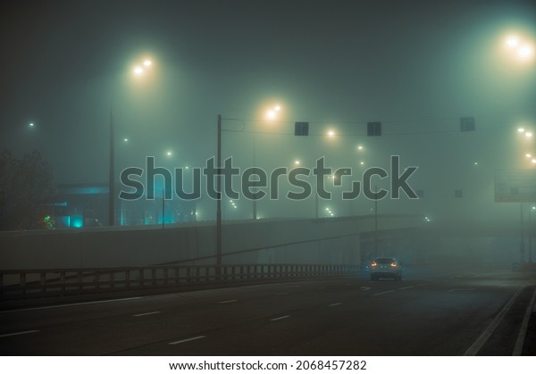 Autumn\
night fog in the city. Lanterns dimly cut through the haze. Heavy\
November evening of Halloween. The street is empty. Lonely cars\
draw red stripes with lights. Dark and\
scary.