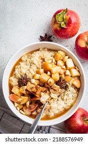 Autumn Oatmeal With Caramelized Apple And Cinnamon In White Bowl, Top View. Winter Cozy Recipe. Healthy Comfort Food.