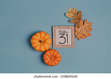 Autumn October Flat Lay. Orange Mini Pumpkins And Calendar Date In Wooden Frame. Halloween Day. Blue Background. Oak Leaves. Fall Mock Up Ideas. Leave A Space. Spooky Day October 31. Small Pumpkins.