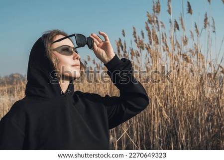 Similar – Blonde woman with black dress and sunglasses performing dance in nature with backlight