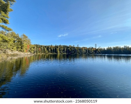 Autumn photos of Northern Ontario Lakes and Trees. Various colours of trees are set against a blue backdrop of the sky. Textures are exaggerated by the rocky shorelines and outcrops.
