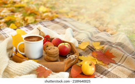 Autumn picnic in the park. Cup of coffee, apple and cookies on picnic plaid on nature yellow leaves. Active lifestyle concept - Powered by Shutterstock