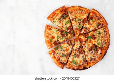 Autumn pizza with pumpkin sauce, gouda and caramelized onions. Sliced. Above view on a white marble background.