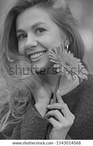 Similar – Young blonde woman portrait laughing outdoors sitting in a garden, and looking at camera.