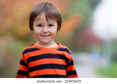Autumn portrait of a boy in the park, smiling at the camera