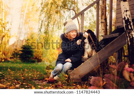 Foto Bild Herbstporträt eines glücklichen Kindes Mädchens, das mit ihrem Hund spielt.