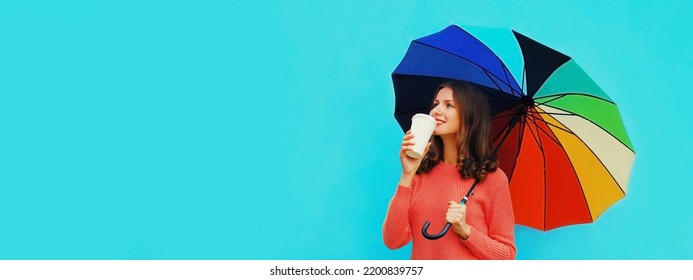 Autumn Portrait Of Happy Smiling Young Woman Holding Colorful Umbrella Wearing Red Knitted Sweater On Blue Background