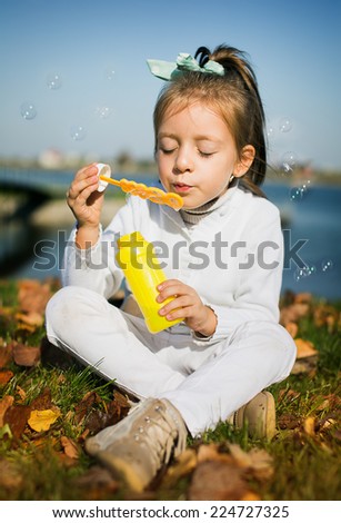 Similar – Adorable little girl playing with a ball sitting on a park bench