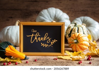 Autumn Pumpkin Decoration With English Text Give Thanks. Wooden Background with Corlorful Rustic Fall Decor Like Leaf And Golden Picture Frame