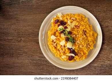 Autumn Pumpkin Risotto With Cranberries And Parmesan Cheese. Top Down View On A Rustic Wood Background.