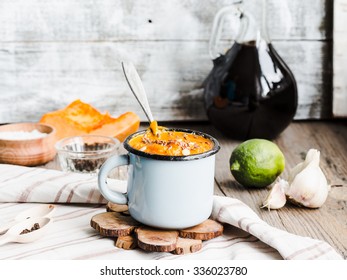Autumn pumpkin soup in a blue mug, rustic background,healthy food