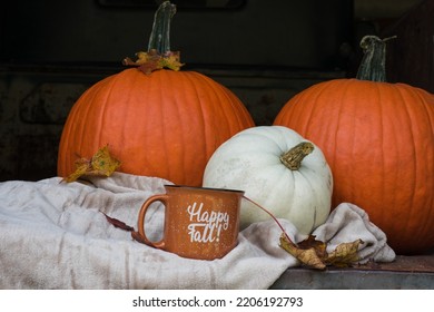 Autumn Pumpkins, Cozy Blanket, And Happy Fall Coffee Mug In The Bed Of An Antique Truck.  