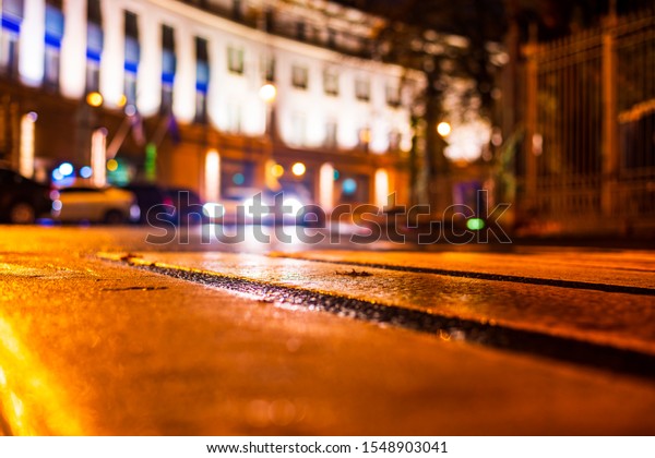 Autumn\
rainy night in the city. Headlights of a riding cars. Parked cars.\
Residential buildings in the city center. Colorful colors. Close up\
view from the level of a pedestrian\
crossing.