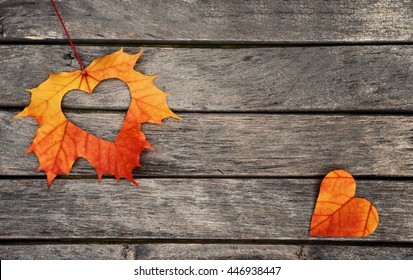 Autumn red and orange leaves with heart.  Fall wooden background. 