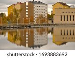 Autumn reflections on the surface of Oulu river. Apartment buildings and the power plant reflections near the dam of Merikoski