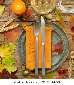 Autumn rustic table setting between leaves and berries on vintage wooden table top view. Thanksgiving, halloween or harvest concept